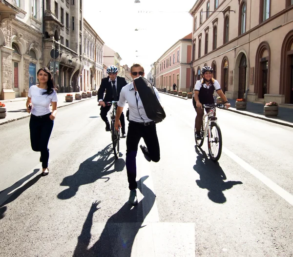 Empresarios andando en bicicleta y corriendo en la ciudad —  Fotos de Stock
