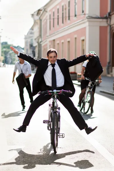 Businesspeople riding on bikes and running in city — Stock Photo, Image