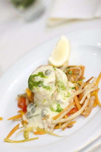 Ein Fischgericht mit weißem Fischfilet mit Buttersoße und Gemüse — Stockfoto