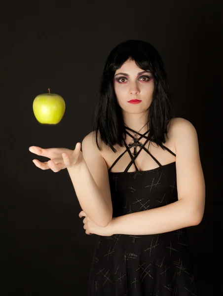 Woman with halloween make up sthrowing green apple — Stock Photo, Image