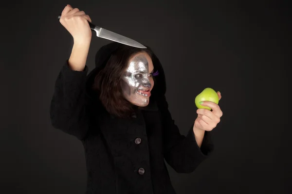 Two-faced witch with green apple and kitchen knife — Stock Photo, Image