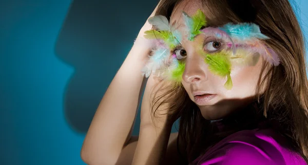Meisje met kleurrijke pluim op haar gezicht — Stockfoto