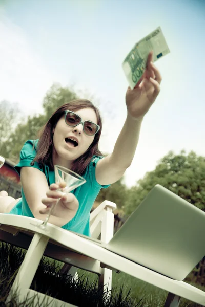 Lounge yalan ve bir banknot ile bir bardağı tutan kadın — Stok fotoğraf