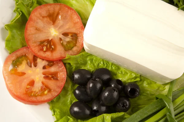 A plate of cut tomato, olives, lettuce and feta cheese — Stock Photo, Image