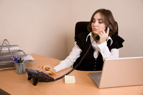 Secretária jovem com telefone e laptop — Fotografia de Stock