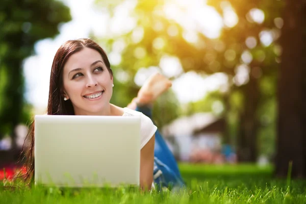 Glada leende flicka på gräs med laptop — Stockfoto