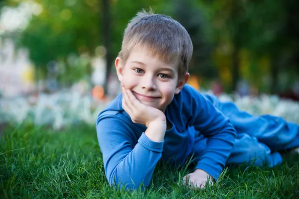 Alegre niño tendido en la hierba — Foto de Stock