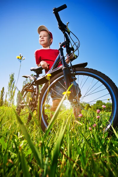 Junge mit Fahrrad steht vor blauem Himmel — Stockfoto