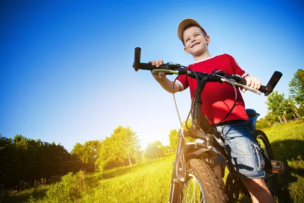Хлопчик з велосипедом, що стоїть на блакитному небі — стокове фото