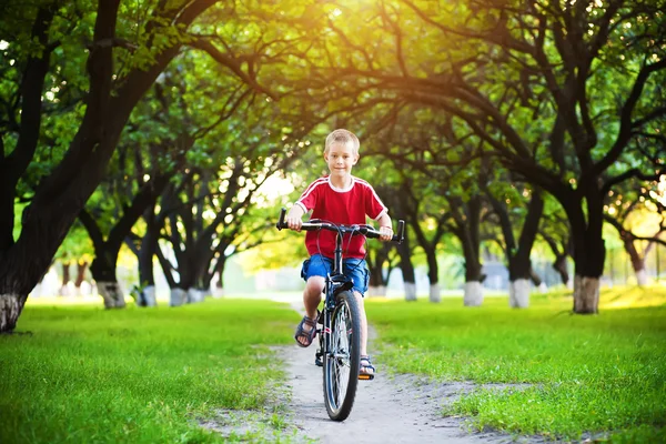Niño feliz monta una bicicleta en el parque — Foto de Stock