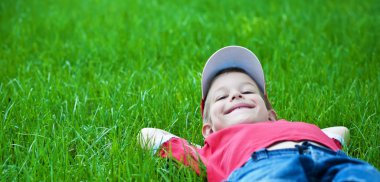 Boy laying on grass. Family picnic in spring park clipart