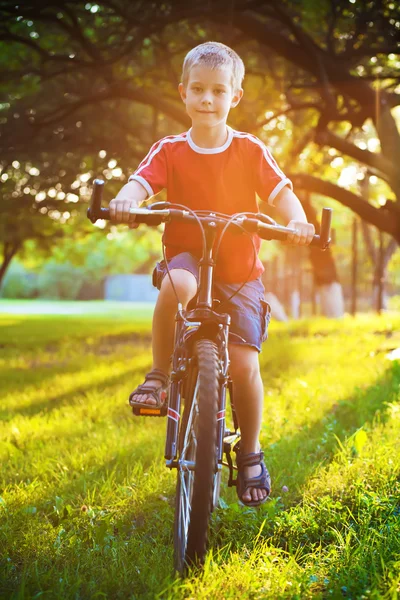 Happy boy rides a bicycle in the park — Stock Photo, Image