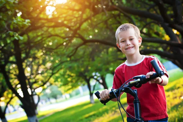 Engraçado menino monta uma bicicleta no parque — Fotografia de Stock