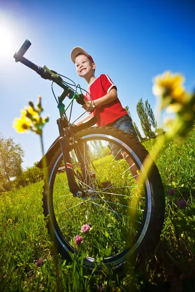 Мальчик с велосипедом стоит на фоне голубого неба — стоковое фото