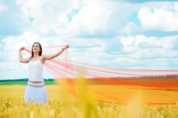 Girl with a red cloth catches wind in the field — Stock Photo, Image