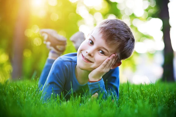 Веселый маленький мальчик лежит на траве — стоковое фото