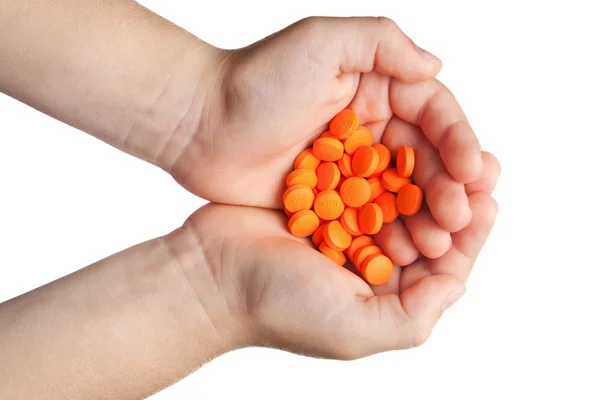 Orange tablets in children's palms — Stock Photo, Image