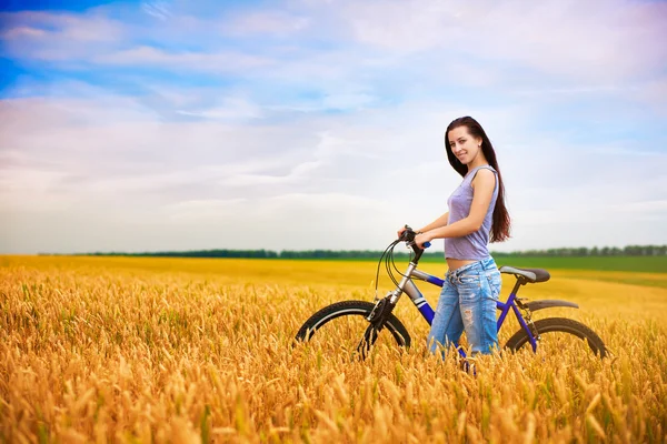 Girl with a bicycle on the wheat field — Stock Photo, Image