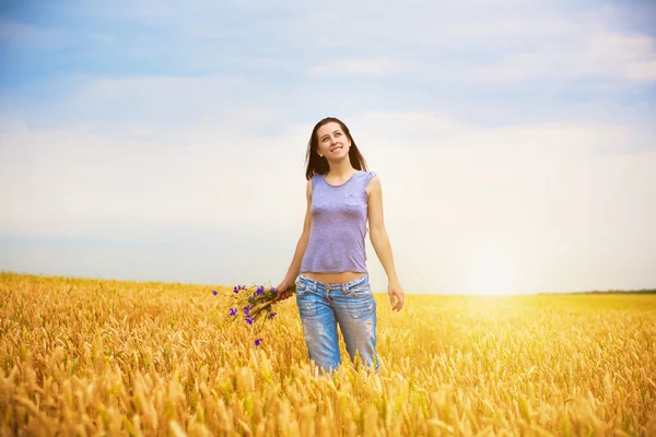 Dívka se trhá květiny na žluté pšeničné pole — Stock fotografie