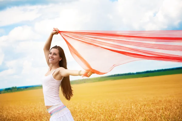 Girl with a red cloth catches wind in the yellow field — Stock Photo, Image