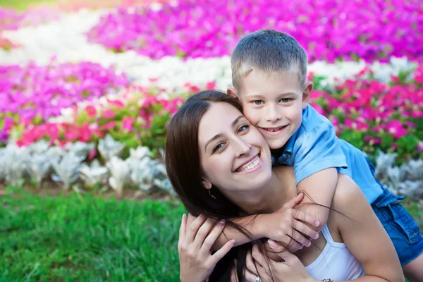Smiling Mother and son siting on grass — Stock Photo, Image