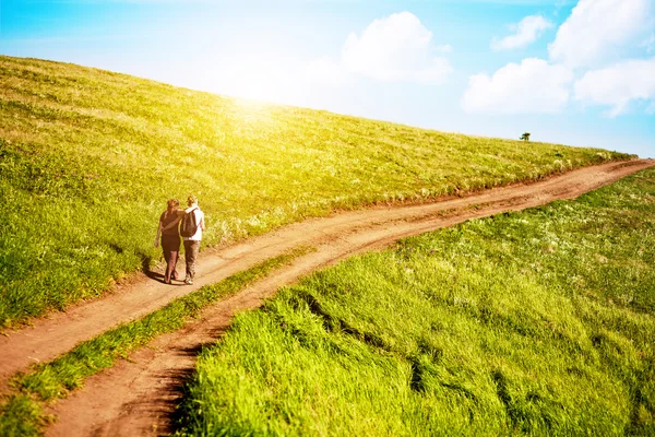 Couple hugging going on a field road — Stock Photo, Image