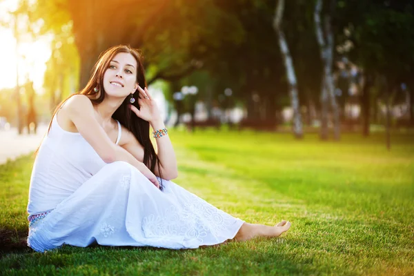 Sonriendo chica bonita joven está sentado en la hierba — Foto de Stock