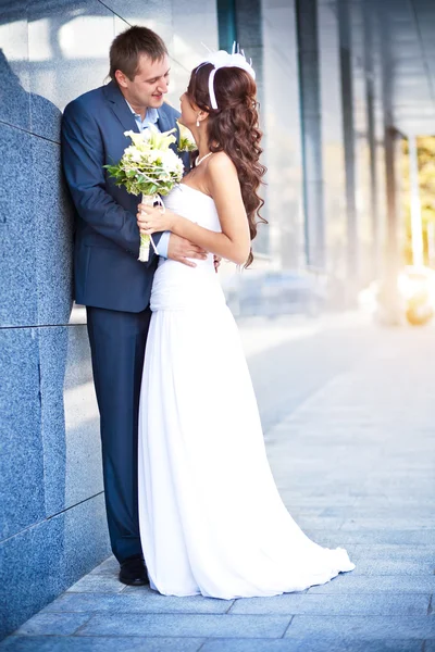 Bruden och brudgummen kysser den granit vägg — Stockfoto