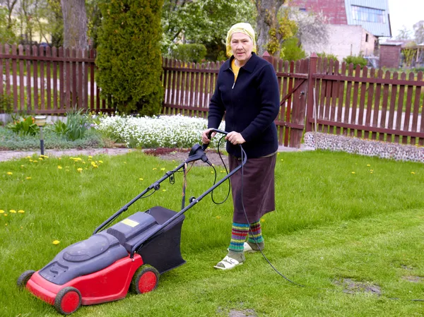 Äldre kvinna som arbetar med gräsklippare — Stockfoto
