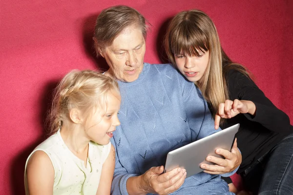 Две девочки и бабушка с помощью цифрового планшета — стоковое фото