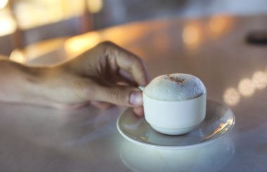 A cup of espresso macchiato held by male hand clipart