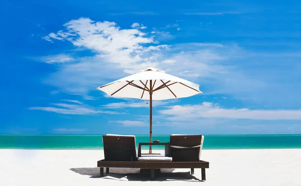Кровати и зонтик на тропическом пляже — стоковое фото