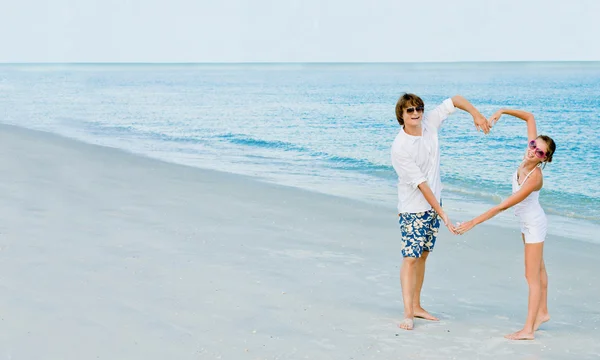 Entzückendes Paar zeigt Herz an einem tropischen Strand — Stockfoto