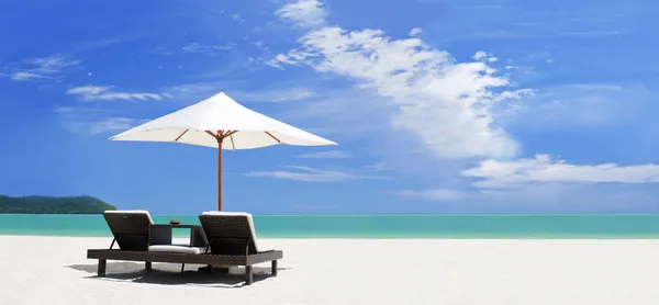 Vista panoramica sulla spiaggia tropicale con ombrellone e due lettini Foto Stock Royalty Free