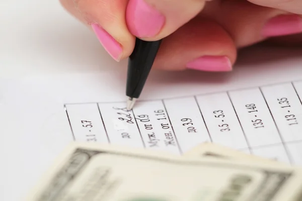 Женская рука с ручкой и бумагой и долларом — стоковое фото