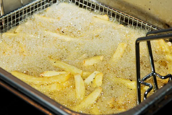French fries in deep fryer — Stock Photo, Image