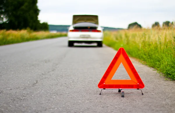 Triángulo rojo de advertencia con un coche averiado —  Fotos de Stock