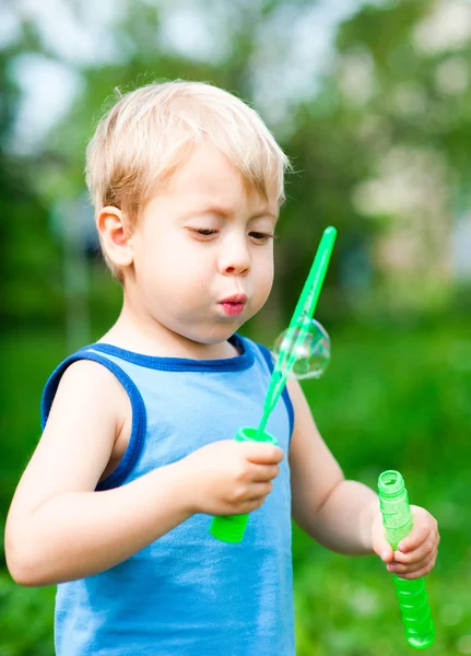 Мальчик надувает пузыри в природе — стоковое фото