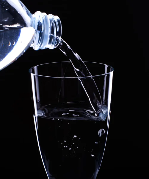 Wasser fließt aus einer Flasche im Glas — Stockfoto