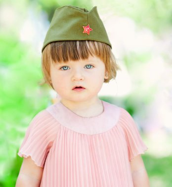 Cute little girl in a soldier's caps clipart