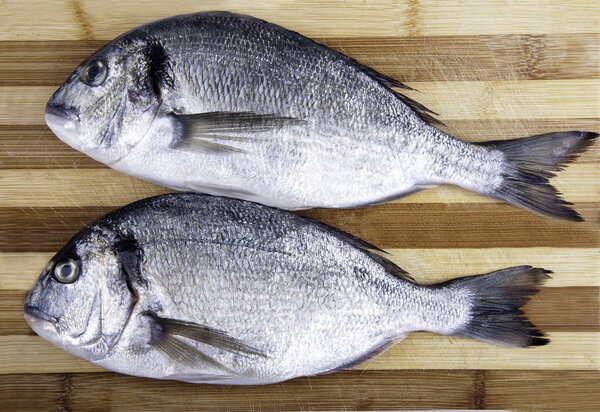 Two fresh sea bream on a cutting board