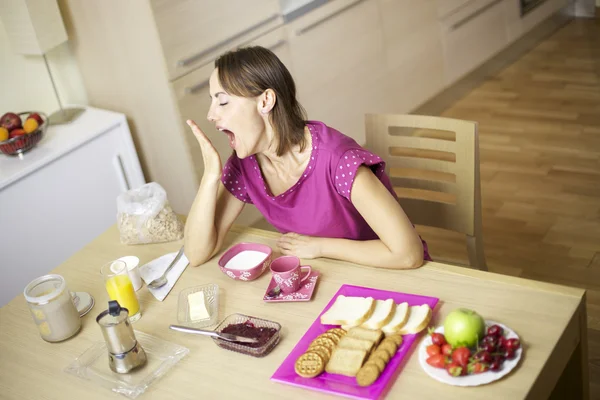 Hermosa modelo femenina bostezando mucho durante el desayuno —  Fotos de Stock