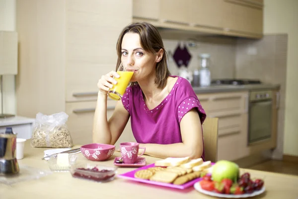 Portrait of female model drinking orange juice at home during breakfast — Stock Photo, Image