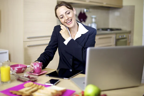 Businesswoman on the phone during breakfast at home — Stock Photo, Image