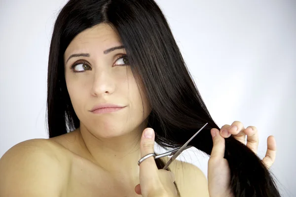 Beautiful female model dubious about cutting her long black hair — Stock Photo, Image