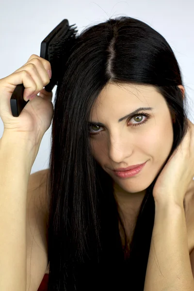 Menina bonita escovando seu longo cabelo preto — Fotografia de Stock