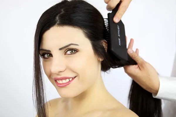 Modelo feminino maravilhoso recebendo cabelo escovado — Fotografia de Stock