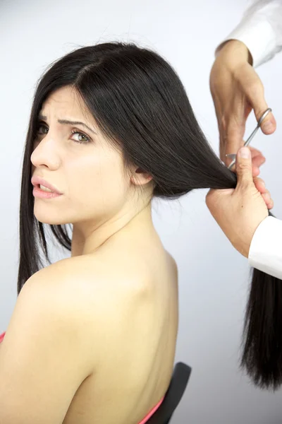 Красива жінка нарізає волосся гострими ножицями — стокове фото
