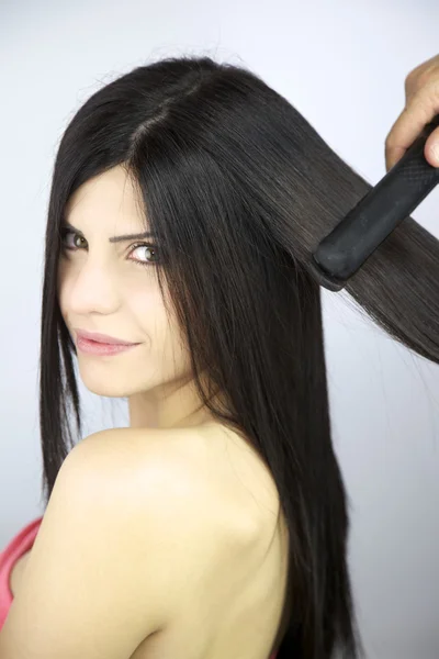 Vacker kvinnlig modell att få långt hår rätade med järn — Stockfoto