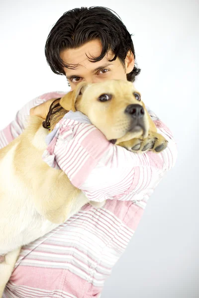 Young man kissing his puppy dog labrador — Stock Photo, Image